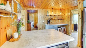 A wooden cabin interior with a kitchen area, including a bar counter and stools. - Lake WI Escape! Explore, Boat, Swim & Hike (Lodi)