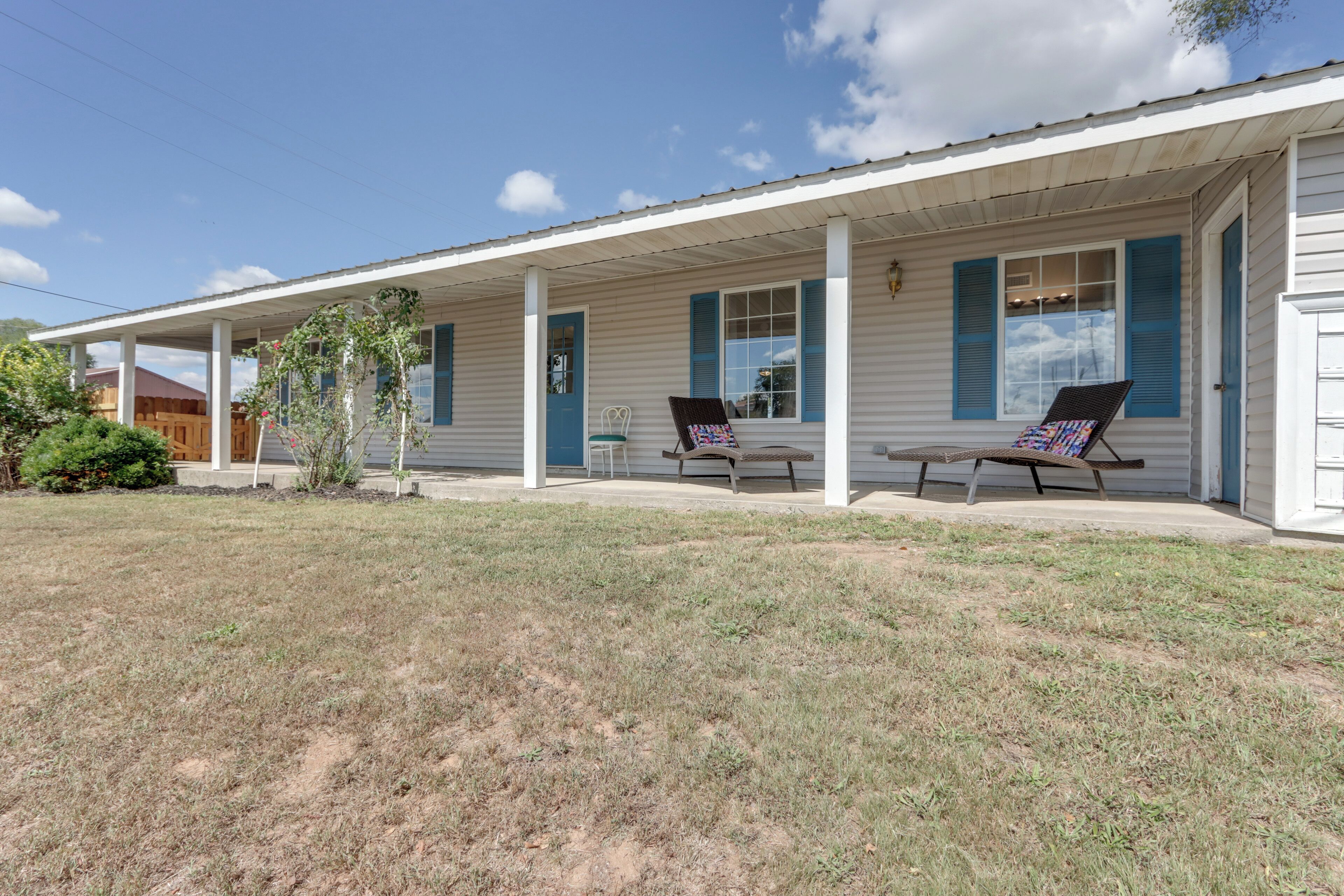 A single-story motel with a covered porch, two lounge chairs, and a small table.