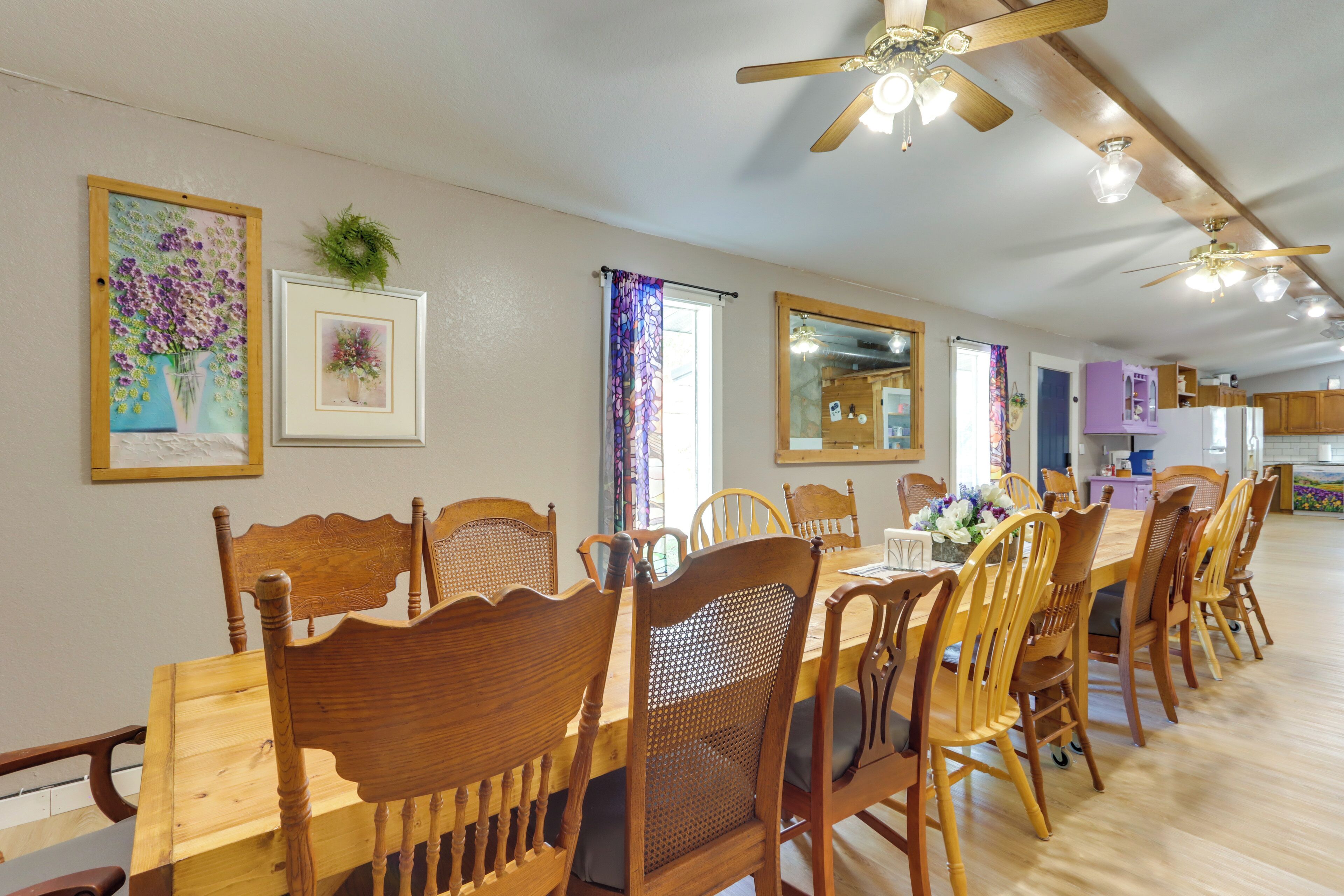 A dining area with wooden tables and chairs, ceiling fans, and framed artwork on the walls.