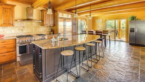 Une cuisine spacieuse dotée d’un grand îlot central, d’appareils électroménagers en acier inoxydable et d’éléments décoratifs en bois.