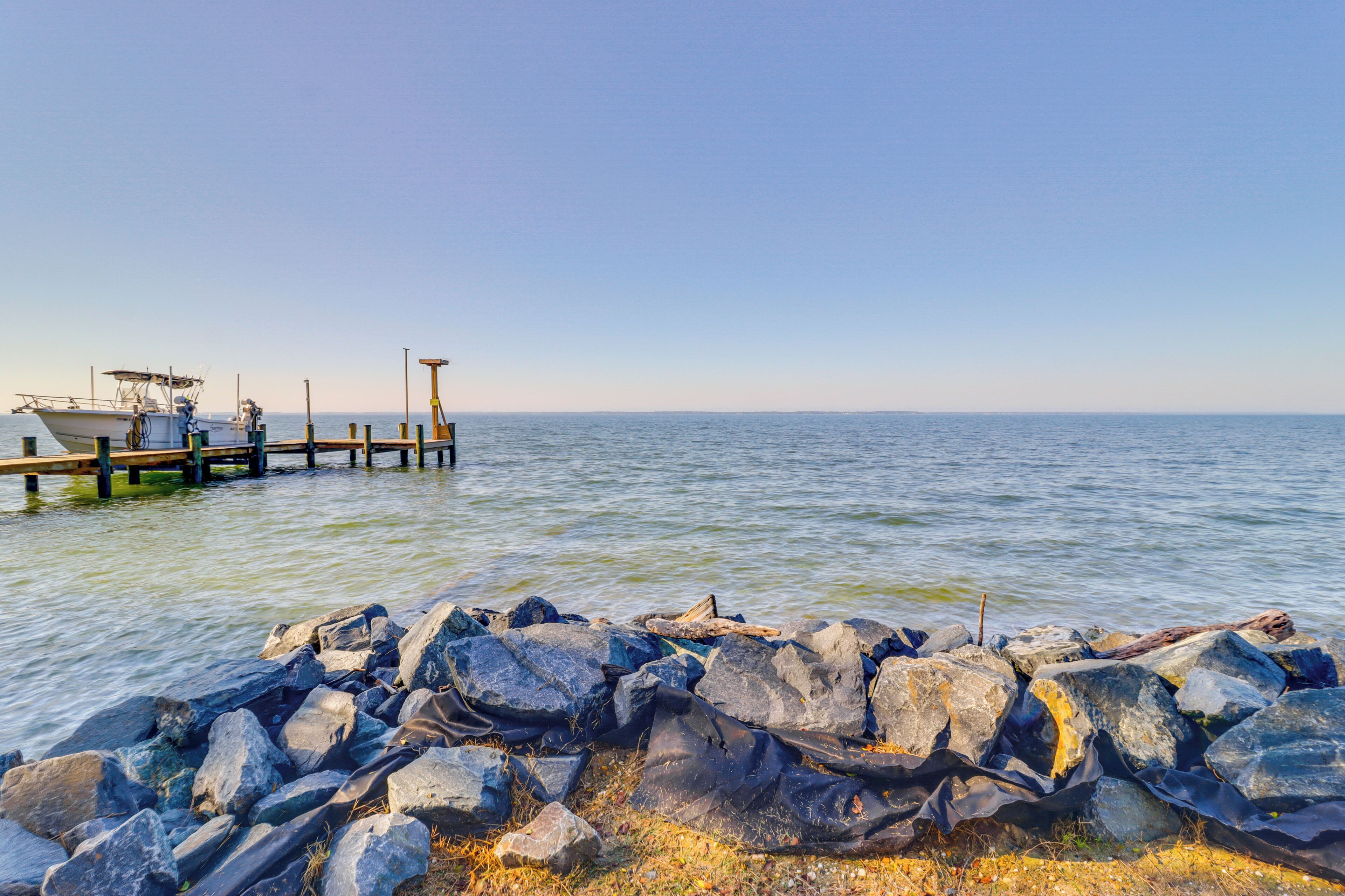A rocky shoreline with a wooden pier extending into calm water.