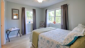 A bedroom with a bed, a ceiling fan, a window with curtains, a chair, and a small table with towels. - Pet-friendly Maryland Home on the Potomac River! (Leonardtown)
