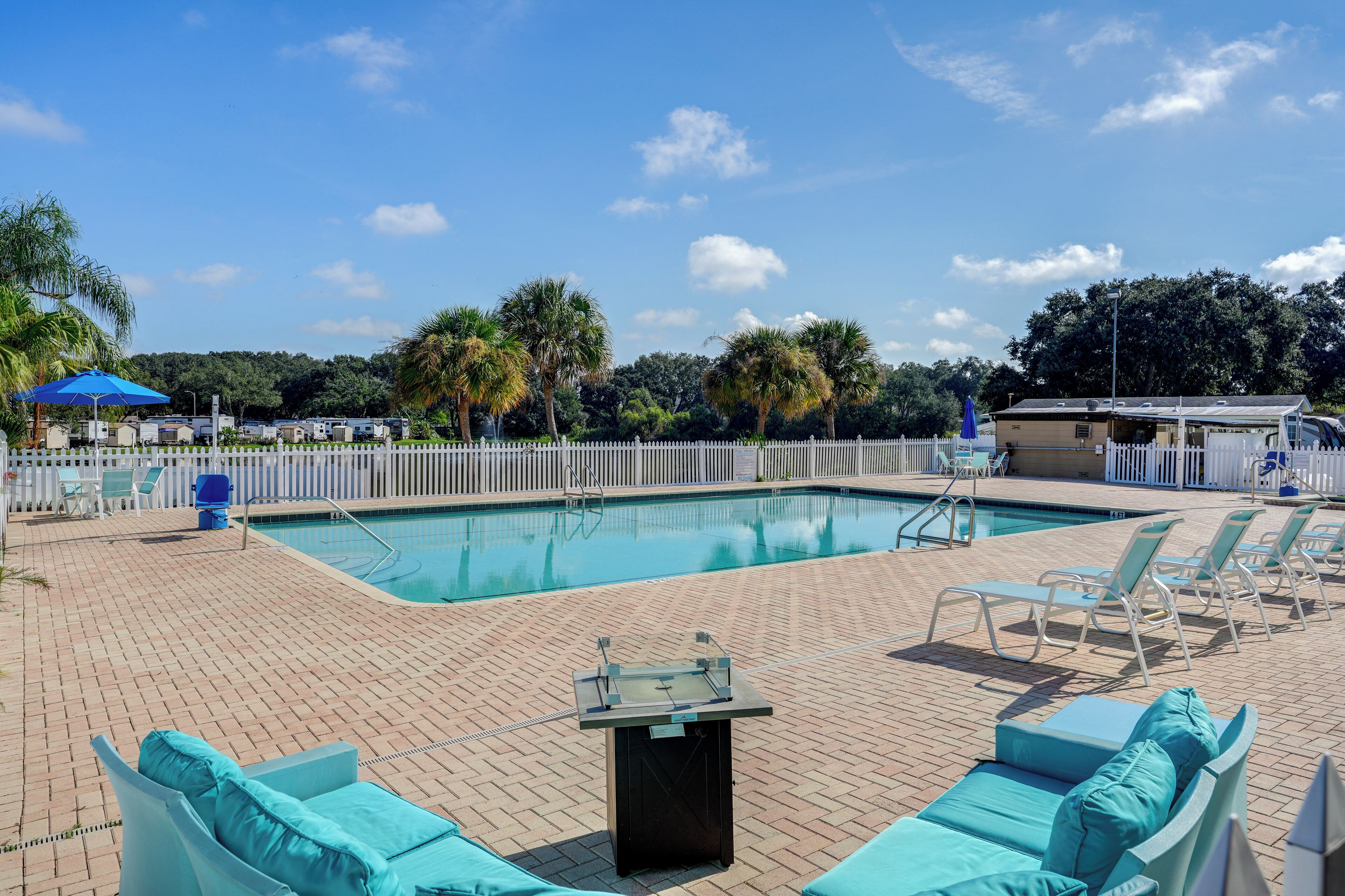 A pool area with lounge chairs, a pool table, and a fenced deck.