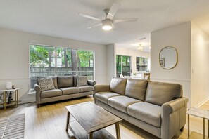 Relax in this stylish living room with leather sofas, a coffee table, and ceiling fan, offering views of the surrounding area.