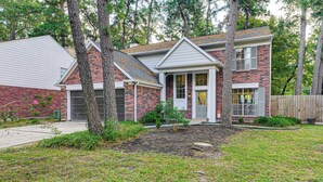 A two-story house with a brick exterior, a front porch, and a well-maintained lawn. - Family Home w/ Game Room & Deck in Spring! (The Woodlands)