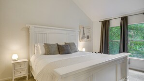 A bedroom with a large bed, a nightstand with a lamp, a window with curtains, and a wall poster. - Family Home w/ Game Room & Deck in Spring! (The Woodlands)