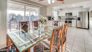 A modern kitchen with a glass dining table, wooden chairs, and a ceiling fan. - 8 Mi to State Farm Stadium: Glendale Home w/ Grill (Peoria)