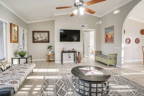 A spacious living room with a ceiling fan, a large flat-screen TV, a sofa, a coffee table, and a bench. - 8 Mi to State Farm Stadium: Glendale Home w/ Grill (Peoria)