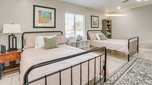 A bedroom with two single beds, a nightstand, a lamp, a bookshelf, and a ceiling fan. - 8 Mi to State Farm Stadium: Glendale Home w/ Grill (Peoria)