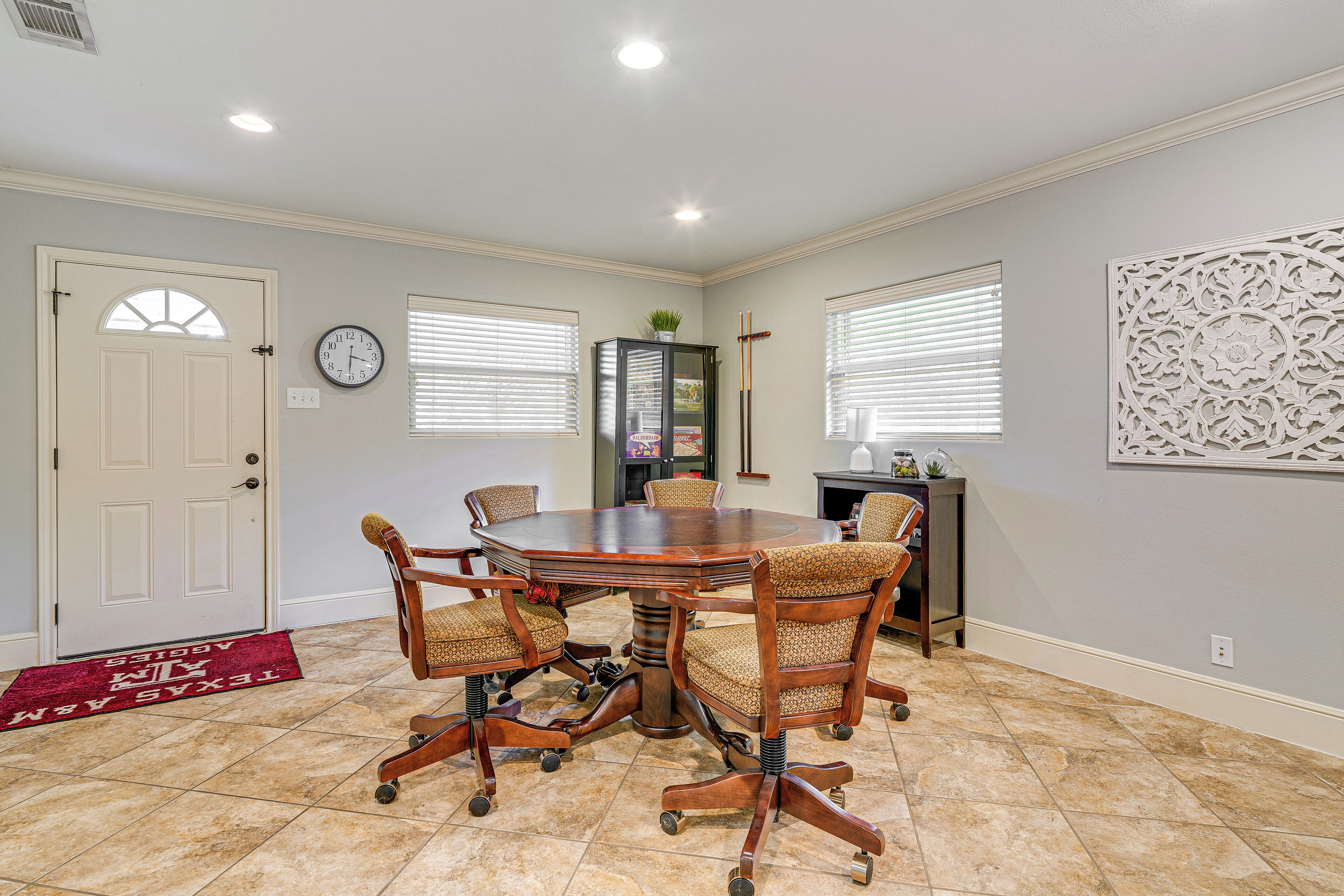 A conference room with a round table, four chairs, a clock, and a decorative wall panel.