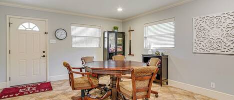 A conference room with a round table, four chairs, a clock, and a decorative wall panel.