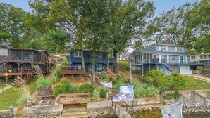 A riverside property with a wooden deck, a small bridge, and a pond. - Dock w/ Deck & Waterslide: Lake of the Ozarks Gem! (Sunrise Beach)