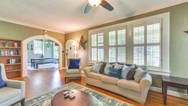 A living room with a sofa, armchairs, a coffee table, and a bookshelf. - Fire Pit, Large Yard: Midtown Columbus Bungalow! (Columbus)