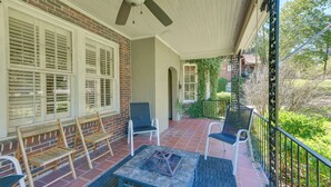 A covered porch with outdoor seating, a fire pit, and a view of the surrounding greenery. - Fire Pit, Large Yard: Midtown Columbus Bungalow! (Columbus)