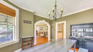 A spacious kitchen with a large wooden table, a chandelier, and a wine tasting sign. - Fire Pit, Large Yard: Midtown Columbus Bungalow! (Columbus)