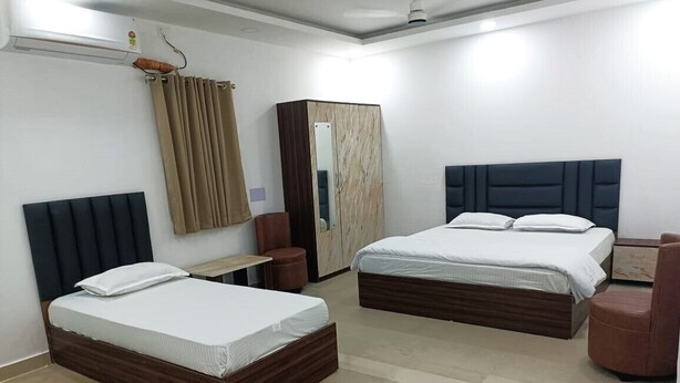A hotel room with two beds, a wardrobe, a mirror, a desk, and a telephone. - HOTEL CORPORATE INN (Supaul)
