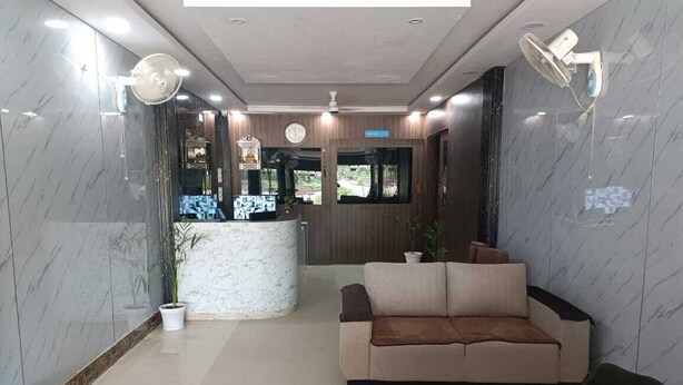 A lobby with a reception desk, a sofa, a fan, and a clock on the wall.