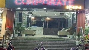 A hotel with a neon sign reading "HOTEL CORPORATE INN" and a balcony with green neon lights.