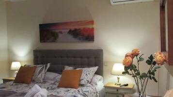Et hotelværelse med en seng, et natbord, en lampe, en vase med blomster og en aircondition.