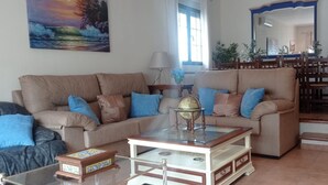 A living room with a sofa, coffee table, and a dining area with chairs and a table. - Perfect for your meetings, adequate space, beautiful, functional, well equipped. (Urda)