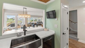 A modern kitchen with a large window, a built-in dishwasher, and a view of the backyard. - Exhale: Renovated, Hot Tub, Golf Course Views (Nags Head)