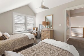 A bedroom with two beds, a dresser, a chair, a lamp, and a large mirror.