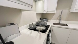 A modern kitchen with white cabinetry, a black countertop, and a stainless steel sink. - London's 1-Bedroom Haven near The Shard in Elephant & Castle (London)