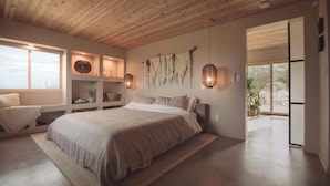 Ein modernes Schlafzimmer mit einem großen Bett, integrierten Regalen und Blick ins Freie.