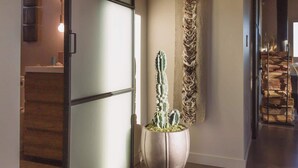 Ein modernes Interieur mit einer Schiebetür, einer Kakteenpflanze und einem strukturierten Wandbehang.
