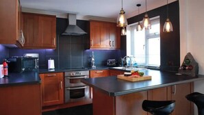 Una cocina moderna con armarios de madera, electrodomésticos de acero inoxidable e iluminación colgante.