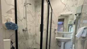 Ein modernes Badezimmer mit einer begehbaren Glasdusche, einer Toilette und einem Waschbecken.