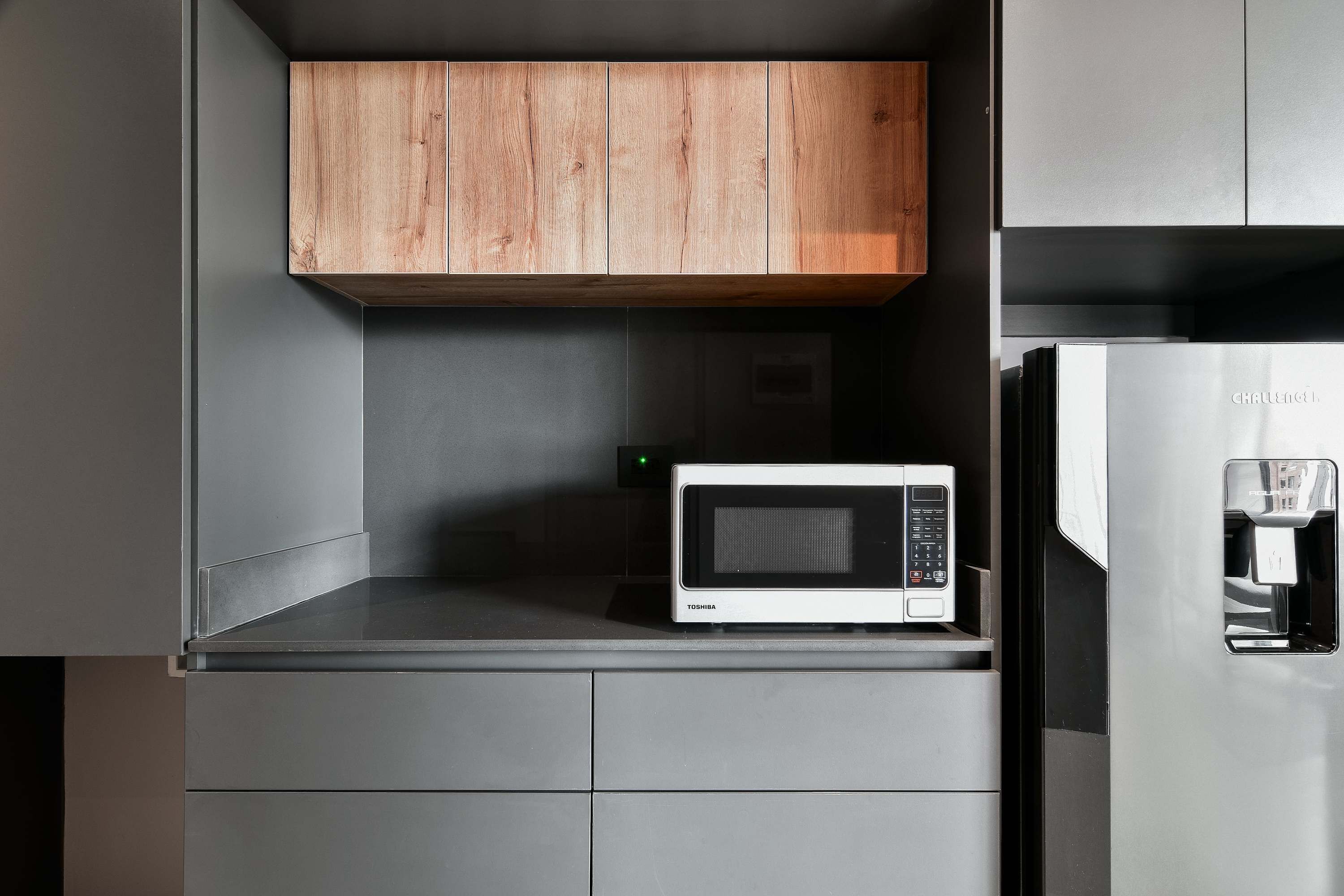 Una cocina con microondas, refrigerador y armarios de madera.