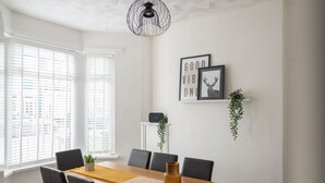 A dining area with a wooden table, six chairs, a hanging light fixture, and framed artwork on the wall. - Host Stay Craddock Street (Cardiff)