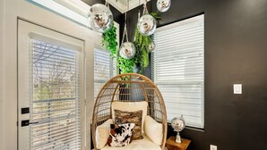Ein Zimmer mit einem Rattan-Sessel, einem weißen Kissen und einem Zierkissen.
