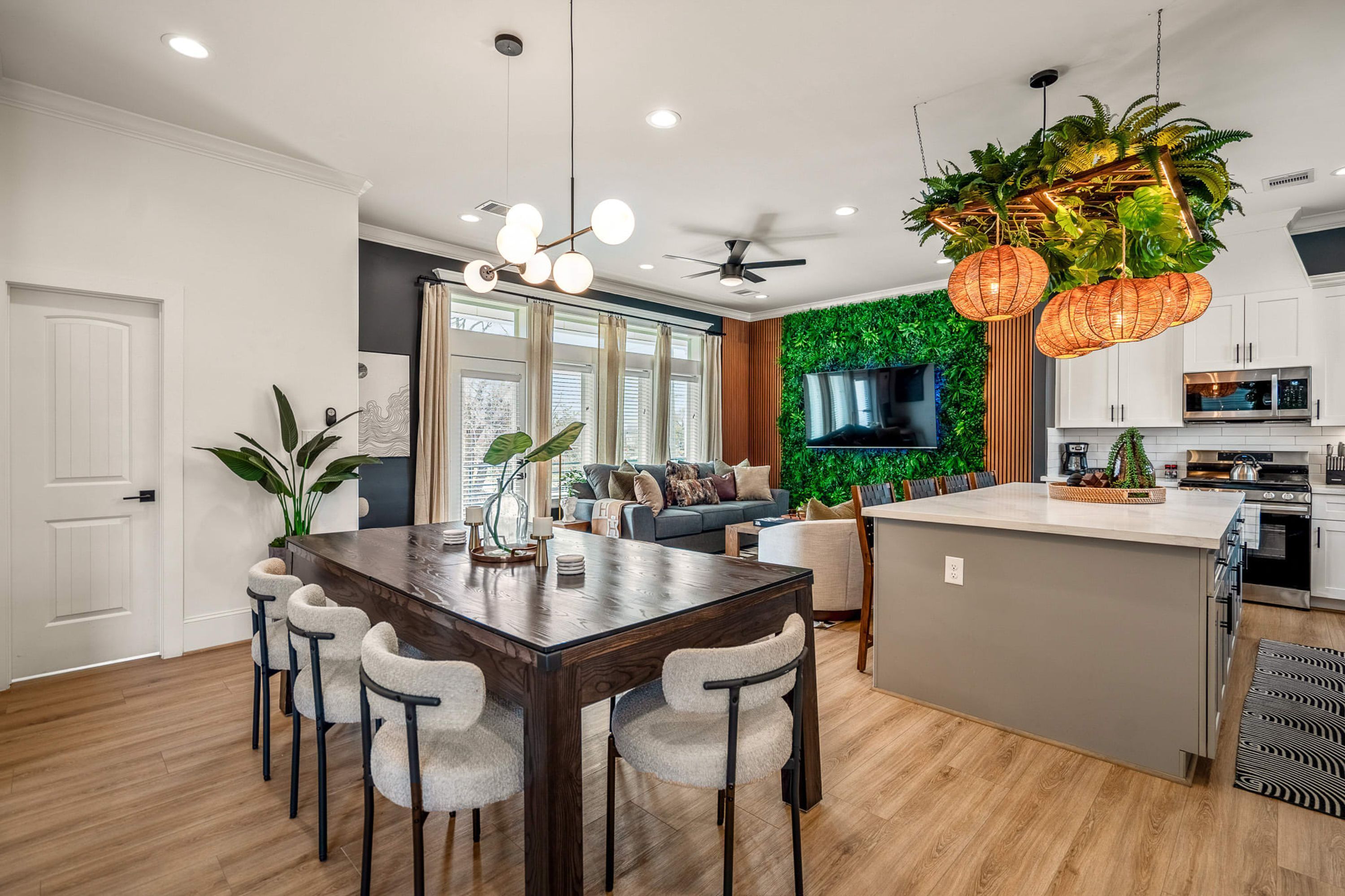 A modern kitchen with a central island, wooden flooring, and a green wall.