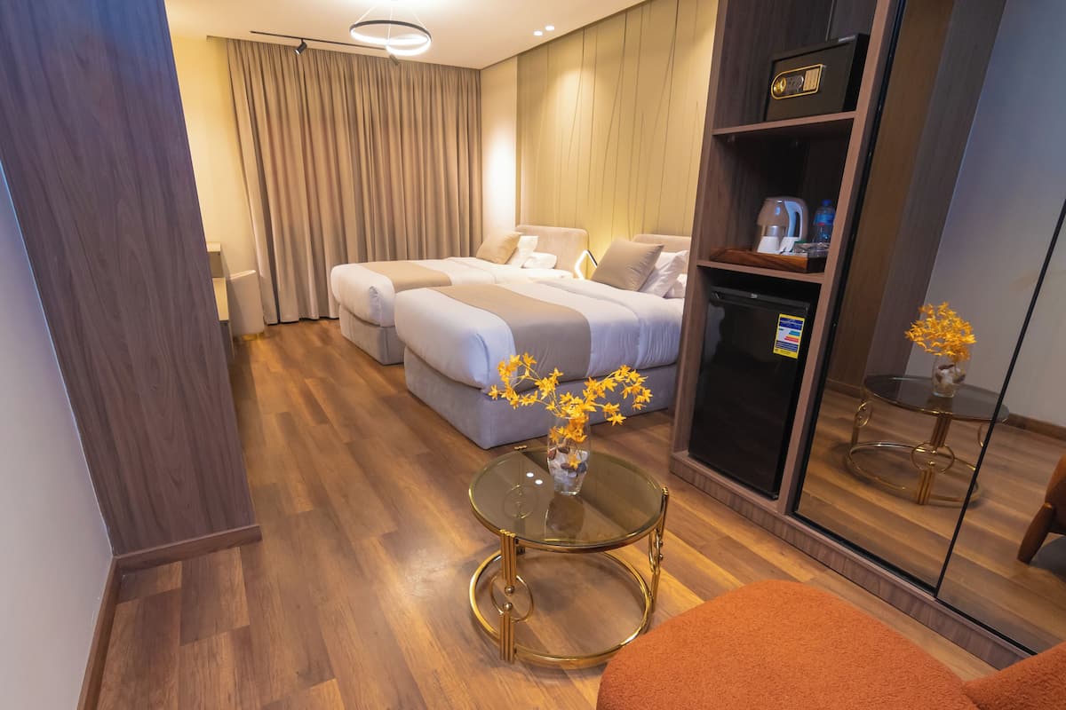 Hotellihuone, jossa on parivuode, sohva, lasinen sohvapöytä ja peili.