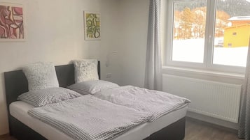 Un dormitorio con cama, ventana y radiador.