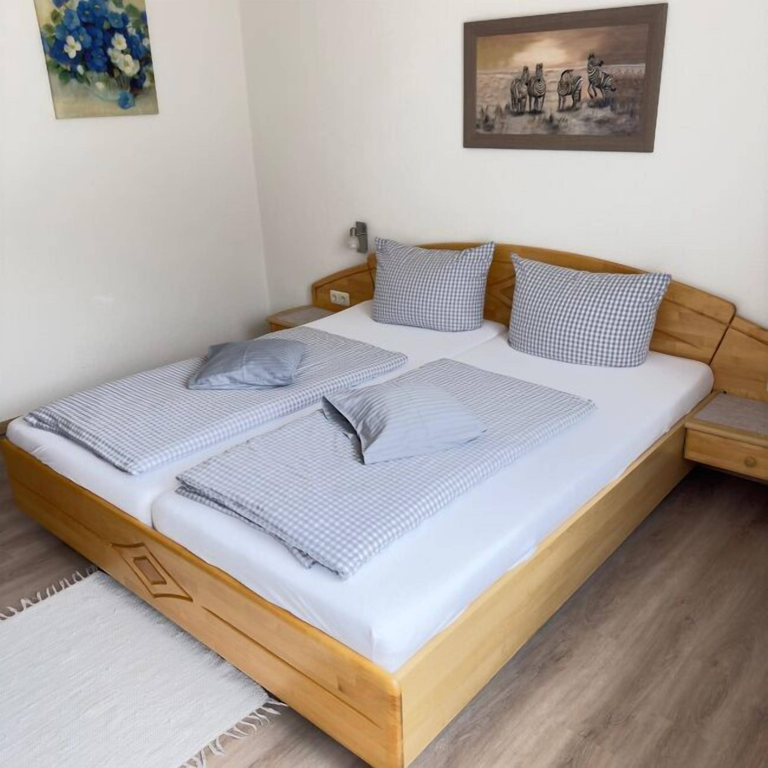 Una cama doble con ropa de cama a cuadros, un cabecero de madera, una mesita de noche y una mesilla.