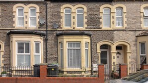 A row of terraced houses with bay windows, a brick facade, and a metal fence. - Host & Stay | Craddock Street (Cardiff)