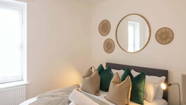 A bedroom with a bed, pillows, a mirror, and wall decor. - Host & Stay | Craddock Street (Cardiff)