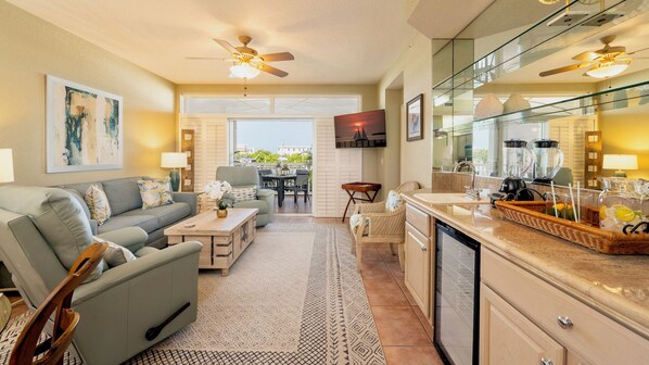 A modern kitchen with a large island, a dining area with a view, and a living room with a sofa and coffee table.