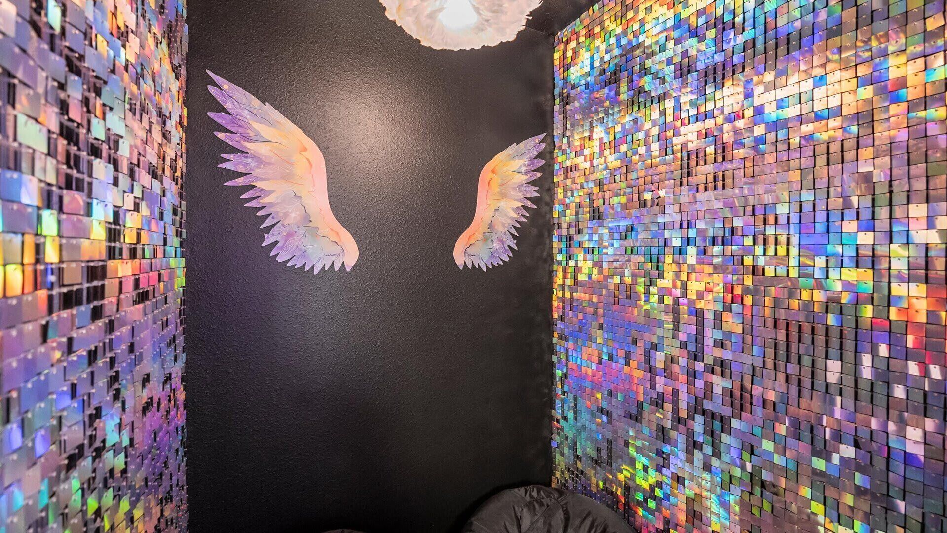 A room with a black wall and a mosaic of colorful tiles.