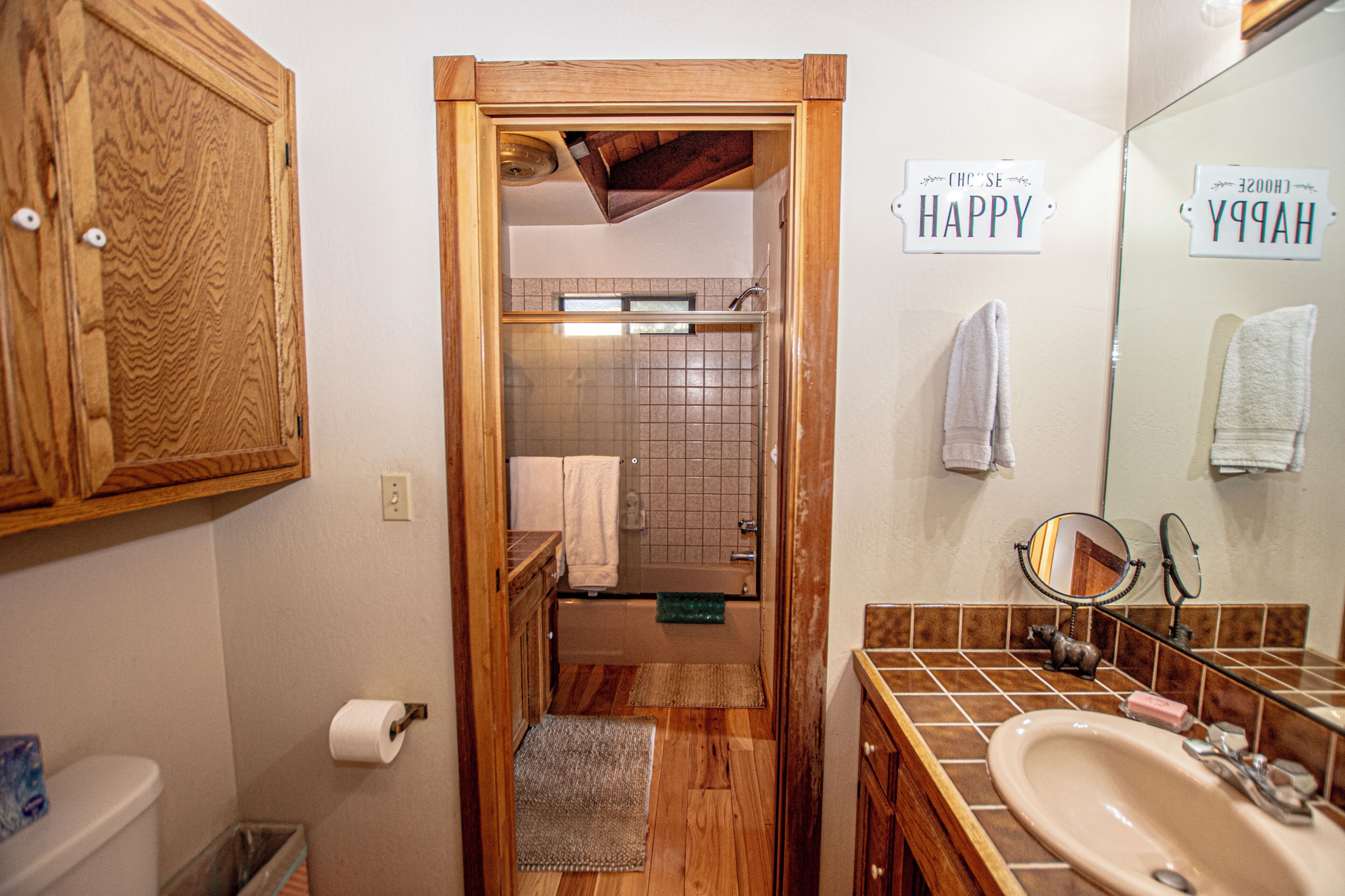 Une salle de bain avec un meuble en bois, un lavabo, un miroir et un porte-serviettes.