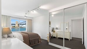 Une chambre d’hôtel comprenant un lit, un bureau, une commode, un miroir et une porte coulissante.