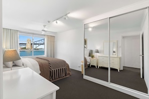 Una habitación de hotel con cama, escritorio, cómoda, espejo y puerta corredera.