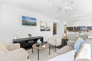 Un salon moderne avec un canapé, des fauteuils, une table basse et des œuvres d’art accrochées au mur.