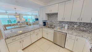 Una cocina moderna con armarios blancos, encimeras de granito y lavavajillas de acero inoxidable.