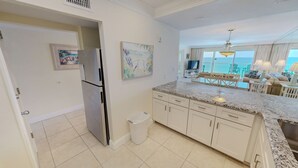 Una cocina con refrigerador, un bote de basura y un comedor con vistas.