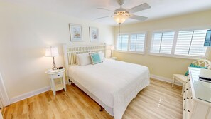 A bedroom with a bed, a nightstand, a lamp, a ceiling fan, and windows with blinds. - Beach House 602a 2 Bedroom Condo (Miramar Beach)