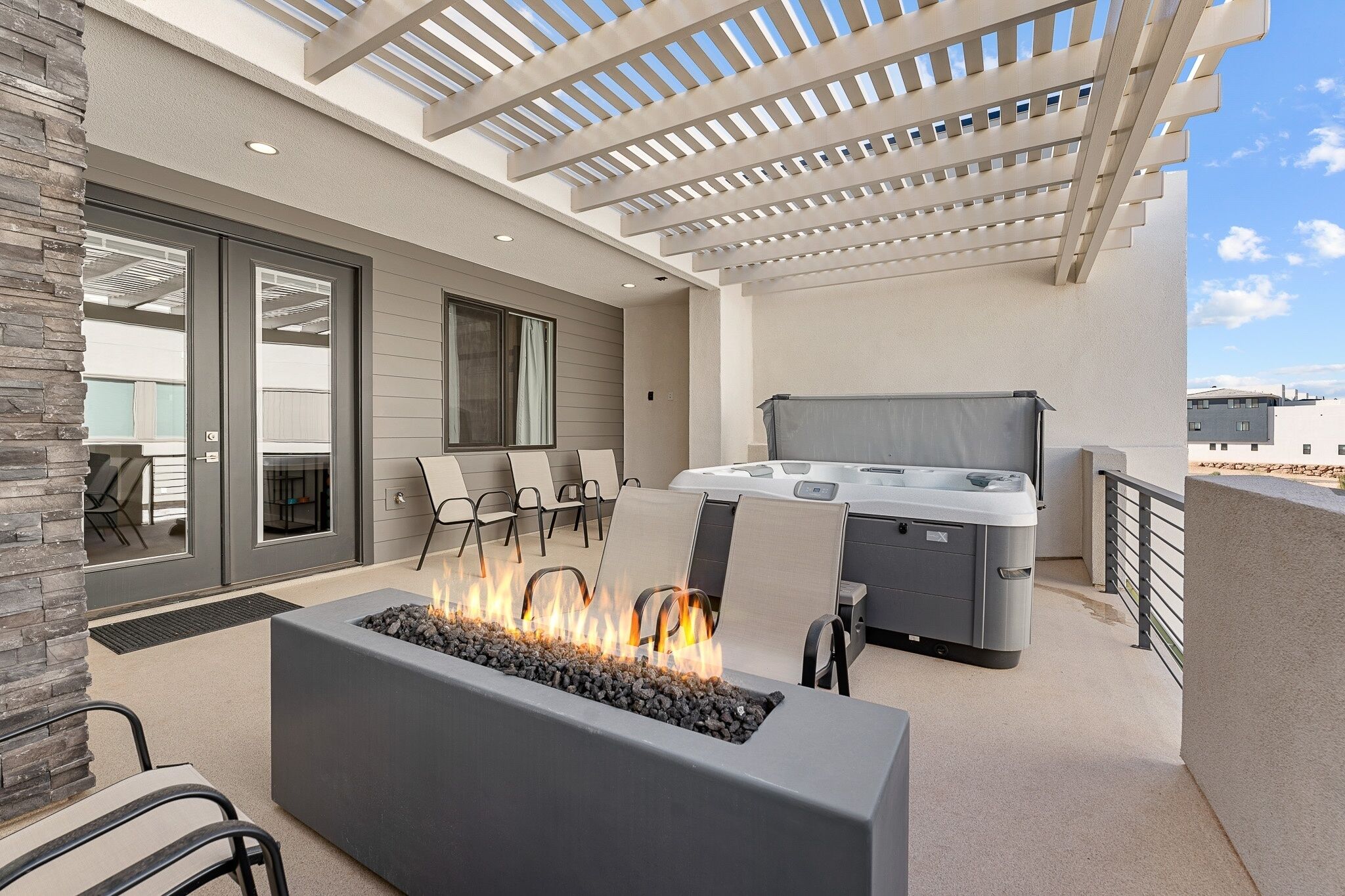 An outdoor patio with a fire feature, seating, and a hot tub.